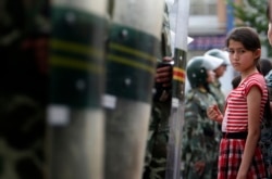 一名维吾尔族女孩儿站在中国武警手持的防暴盾前。(2009年7月9日)