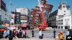 2024年4月3日星期三,台湾候任总统兼副总统赖清德(中左红衣)在台湾东部花莲参观地震后部分倒塌的建筑物现场。
