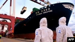 身穿防护服的中国海关人员在山东省青岛港检查一艘货轮。(2020年11月16日)