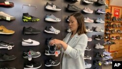 在这张2019年8月28日拍摄的照片中,家人在旧金山拥有 Footprint 鞋店的詹妮弗·李 (Jennifer Lee) 站在一堵运动鞋的墙边,其中许多运动鞋是中国制造的。