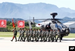 在台湾阿帕奇部队成军仪式上,一组飞行员走过一架AH-64E阿帕奇武装直升机。(2018年7月17日)