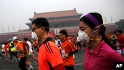 参加北京国际马拉松长跑的人在雾霾中跑过天安门,有些人带着口罩(2014年10月19日)