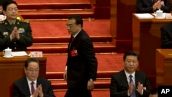 在全国人大开幕式上,中国总理李克强(中)从国家主席习近平(右)身后走上台做报告。(2016年3月5日)