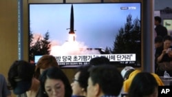 人们在韩国首尔一个地铁站的屏幕前看朝鲜导弹试射的新闻,2019年7月25日
