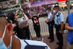 香港警察在维多利亚公园外拦截一名妇女,她身穿纪念六四的T恤,做出反送中运动“五大诉求 缺一不可”的手势。(2021年6月4日)