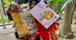 陈先生展示当局送赠的海味福袋内其中两件产品,包括花菇及即食鲍鱼 (美国之音/汤惠芸)