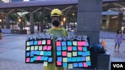 一位自称参加了香港“反送中运动”所有大游行的香港女学生在台北车站广场举起“连侬板”。(2019年7月27日,美国之音林枫拍摄)