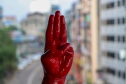 一名反军事政变抗议者用红漆染红的手举手行三指礼。(2021年4月6日)