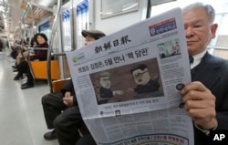 一位乘客在韩国首尔的地铁列车上阅读报道朝鲜领导人金正恩与美国总统唐纳德·川普计划举行高峰会议的报纸。(2018年3月10日)