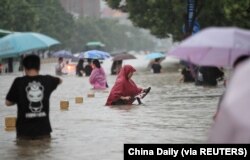 Warga mengarungi banjir di jalan yang banjir di tengah hujan deras di Zhengzhou, Provinsi Henan, China, 20 Juli 2021. (Foto: China Daily via REUTERS)