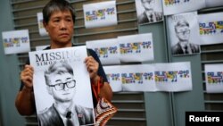 一名妇女手举英国驻港总领馆前职员郑文杰的画像在英国驻港总领馆外抗议。(2019年8月21日)