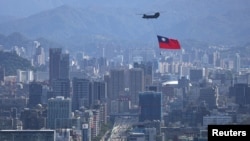 一架悬挂台湾旗帜的支奴干直升机在台北市上空飞行。(2021年10月7日)