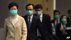 戴着口罩的香港特首林郑月娥带领港府官员步入一个新闻发布会会场。(2020年1月31日)