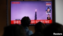 韩国民众在电视上观看有关朝鲜发射弹道导弹的电视报道(路透社2021年10月19日)
