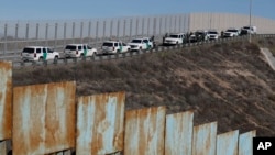 美国墨西哥边界的隔离墙和巡逻车,警察回应一群非法穿越边界墙的中美洲移民(2018年12月9日)。