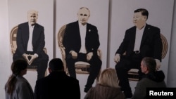 资料照片:在克里米亚雅尔塔的里瓦几亚公园的一座艺术画廊,访客驻足观看描绘俄罗斯总统普京与美国总统特朗普和中国国家主席习近平坐在一起的题为《雅尔塔2.0》的艺术作品。(2025年2月8日)