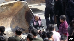 从土改时的“打土豪,分田地”到如今有人戏称的“打农民,占田地”。图为2007年河南郑州一村庄的反拆迁村民坐在推土机前