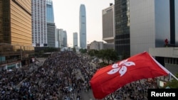 9月29日,香港抗议者封堵了通往金融区的道路。他们不顾警方用催泪弹和警棍发动的攻击举行大规模集会。图为参加集会的一名抗议者挥舞香港旗帜。