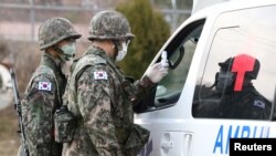 戴着口罩的韩国士兵在大邱的一个军营哨卡检查一辆救护车。(2020年2月26日)