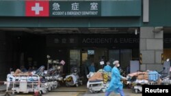 2022 年 2 月 17 日在香港爆發新冠病毒病後,穿著個人防護設備的醫務人員在醫院外設立的臨時治療區的病床上工作 (路透社照片)