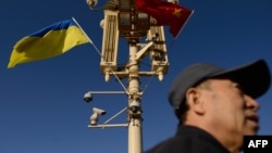 资料照:一名男子走过北京天安门广场灯柱上悬挂的中国与乌克兰国旗。(2013年12月5日)