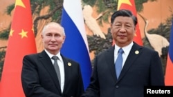 资料照片:2023 年10月18日,俄罗斯总统弗拉基米尔·普京在中国北京举行的“一带一路”论坛上与中国国家主席习近平握手。
