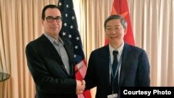 2018年10月10日,美国财政部长姆努钦和中国人民银行行长易刚在国际会议期间握手,姆努钦说双方讨论了重要经济问题(姆努钦推特图片)。