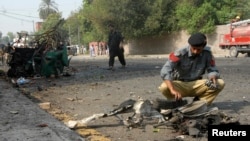 A police officer collects evidence from the site of a bomb attack on a Frontier Corps (FC) convoy in Peshawar, Sept. 23, 2014.