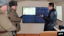 金正恩在观看导弹试射期间与官员谈话。(2022年1月11日)