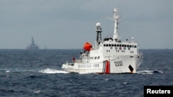 资料照:一艘中国海警船在南中国海上的一座中国海上钻井平台旁驶过。(2014年6月13日)
