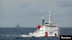 资料照:一艘中国海警船在南中国海上的一座中国海上钻井平台旁驶过。(2014年6月13日)