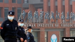 在世卫组织新冠病毒源头调查组视察武汉的中国科学院病毒研究所期间,中国保安人员在研究所外站岗。 (路透社 2021年2月3日)