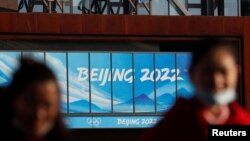 戴着口罩的人们在北京2022年冬奥会和冬残奥会组委会办公大楼附近(资料照片)