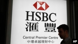 资料照:一名男子走过香港汇丰银行一个支行的广告灯箱。