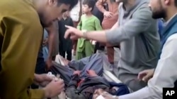 视频截图显示喀布尔机场外发生炸弹袭击事件后,人们在照料受伤者。(2021年8月26日)