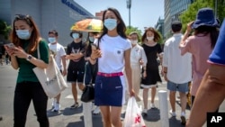 北京,人们戴着口罩穿过一个十字路口(2020年6月5日)。