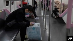 乘坐武汉地铁的乘客在看手机。(2020年4月1日)