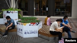 北京的一条商业街上的商店门口站着一名向往张望的销售员。(2021年9月15日)