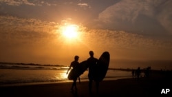 资料照片:加利福尼亚州洛杉矶威尼斯海滩夕阳下的冲浪者。(2021年6月16日)