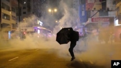 资料照片:2020年元月1日,香港一名抗议者在警方施放催泪弹时撑着雨伞。