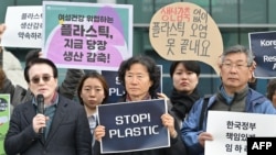 2019 年 11 月 25 日,在釜山联合国塑料污染政府间谈判委员会第五届会议 (INC-5) 举办场外,一名活动人士与其他抗议者一起举着“停止塑料”的标语。