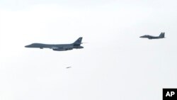 韩国国防部提供的图片显示,一架美国空军B-1B“枪骑兵”战略轰炸机(左一)往朝鲜半岛投下一颗炸弹。(2017年7月8日)