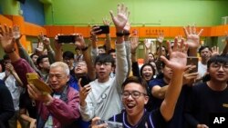 香港选民在他们支持的一名民主派候选人在区议会选举中获胜后举手欢呼。(2019年11月25日)