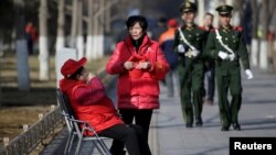 北京长安街旁巡逻的武警和带着红袖章、自称为治安志愿者的北京大妈。(2017年3月2日)