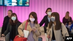 乘客们在抵达加州洛杉矶国际机场时戴上防护口罩,以防冠状病毒的传播(2020年1月22日)。