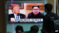 2018年4月18日,在韩国首尔火车站,人们观看电视新闻节目,屏幕上显示美国总统唐纳德·川普和朝鲜领导人金正恩各自的肖像。