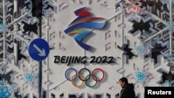 北京街头一名男子走过一幅北京冬奥会的宣传画前。(2022年1月25日)