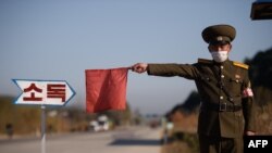 一名朝鲜军人正在示意一辆出租车停下,接受消毒。(法新社 2020年12月29日)