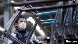戴着口罩的工人在上海延锋安道拓工厂汽车座椅的生产线上工作。(2020年2月24日)